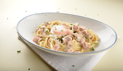 carbonara pasta with chicken ham and half boiled egg in creamy cheese white sauce in white background western halal menu