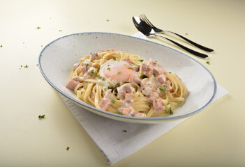 carbonara pasta with chicken ham and half boiled egg in creamy cheese white sauce in white background western halal menu