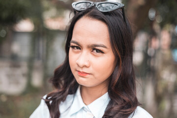 Closeup portrait of a skeptical young woman expressing her doubts. Outdoor scene.