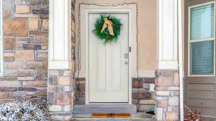 Pano Facade of home with holiday wreath on the front door framed with string lights