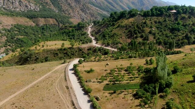 Scenic Downhill Road With Traveling Car On Ugam-​Chatkal National Park Near Mountain Urungach Lakes. - Aerial Drone Shot