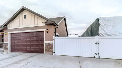 Pano Truck in an open parking area with white gate beside attached garage of house