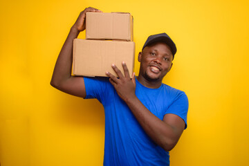 An African delivery or dispatch man with blue shirt carrying boxes and wearing a face cap