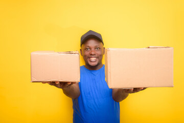 An African delivery or dispatch man with blue shirt carrying boxes and wearing a face cap
