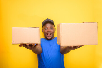 An African delivery or dispatch man with blue shirt carrying boxes and wearing a face cap