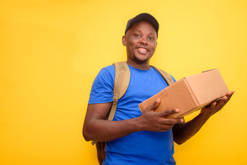 An African delivery or dispatch man with blue shirt and a back pack , carrying boxes and wearing a...