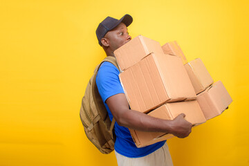 An African delivery or dispatch man with blue shirt and a back pack , carrying boxes and wearing a...