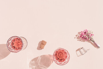 Two glasses with rose wine, small bouquet of flowers in bright sunlight. Summer romance concept.
