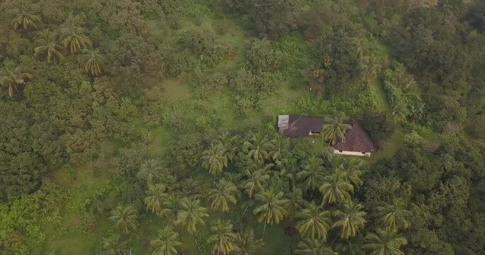 Isolated Structure Surrounded By Green Lush Vegetation During Spring Near Cotigao Wildlife Sanctuary Netravali, South Goa, India. - Aerial Orbiting Shot 