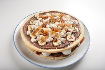 baked chocolate banana pizza with marshmallow and dry grape fruit dessert for kids in white background western halal menu