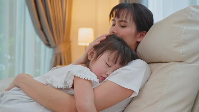 Asian beautiful loving mother hugging sleeping baby girl in her arms.
