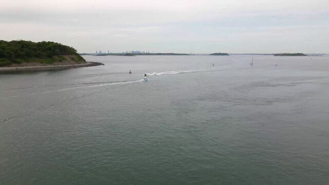 Static drone shot of two motor boats crossing paths.  Boston Cityscape in far distance.  Aerial