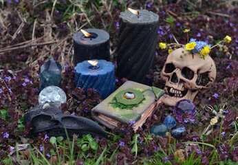 Still life with Beltane ritual objects, skull, burning candles, crystals and magic book of spells.