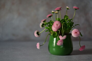 Bouquet of pink daisies in a green mug.
