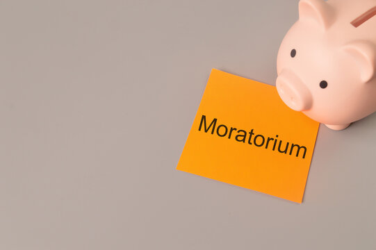 Piggy bank and orange note written with MORATORIUM. Copy space