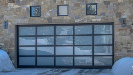 Pano Home with stone wall and glass garage door viewed during winter in Park City