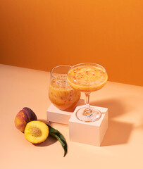 Juice fruit drink made from fresh ripe peach in a glass on a modern abstract podium orange...