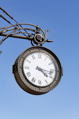 Antique round clock with Roman numerals hang on the street of the city