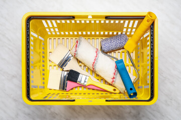 Shopping basket with painter's supplies on light background