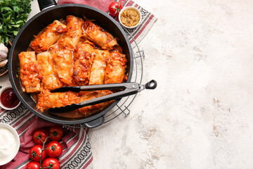 Frying pan with tasty stuffed cabbage rolls on light background