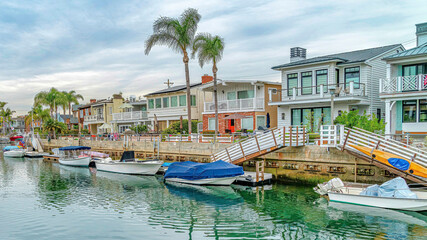 Fototapeta na wymiar Pano Waterfront houses with view of stairs going down boat docks at a scenic canal