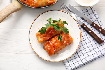 Plate with tasty stuffed cabbage rolls on light wooden background