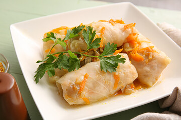 Plate with tasty stuffed cabbage rolls on color wooden background