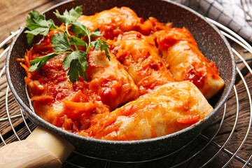 Frying pan with tasty stuffed cabbage rolls on wooden background