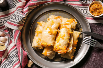 Plate with tasty stuffed cabbage rolls on dark background