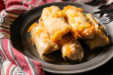 Plate with tasty stuffed cabbage rolls on dark background