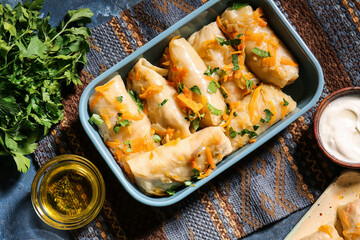 Baking dish with tasty stuffed cabbage rolls on color background
