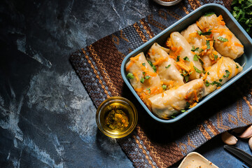 Baking dish with tasty stuffed cabbage rolls on color background