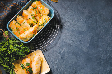 Baking dish with tasty stuffed cabbage rolls on dark background