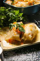Plate with tasty stuffed cabbage rolls on dark background