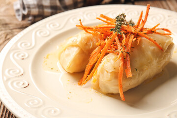 Plate with tasty stuffed cabbage rolls on wooden background, closeup