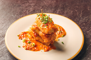 Plate with tasty stuffed cabbage rolls on dark background