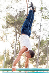 Man doing handstand on bars in the park.
