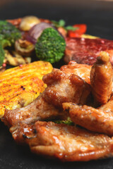 Hot spicy fried set. Grilled chicken, pork and beef over black background, with BBQ vegetables.