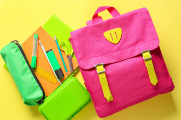 School backpack with stationery on color background
