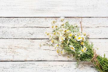 Bouquet of beautiful chamomile flowers on light wooden background