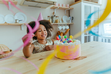 Happy girl looking at the birthday cake with candles