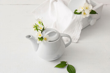 Composition with teapot and beautiful jasmine flowers on light background