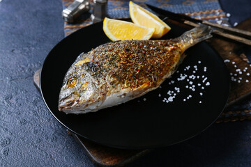 Plate with fried dorado on color background