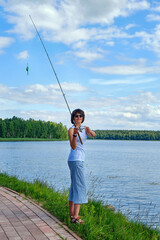 woman fishing on a spinning rod in the lake on summer day, outdoor activities