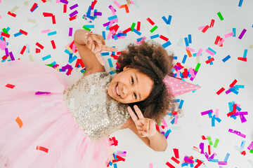 Happy girl in party hat lying on white background