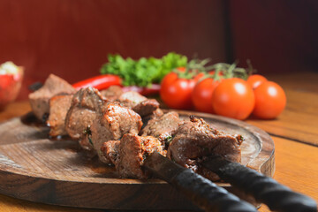 Marinated shashlik cooked on a barbecue grill over charcoal. Shashlik or Shish kebab served on a wooden board