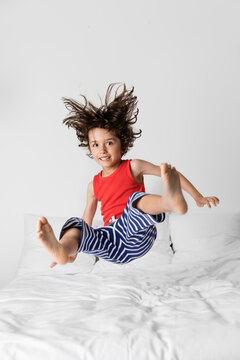 little boy jumping on a white bed in mid-air