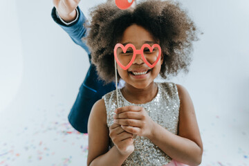 Happy girl and boy having fun time on the party with paper decor eyeglasses