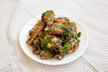 Homemade baked Garlic Parmesan Chicken Wings on a white plate, low angle view.