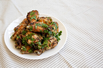 Homemade baked Garlic Parmesan Chicken Wings on a white plate, low angle view. Space for text.